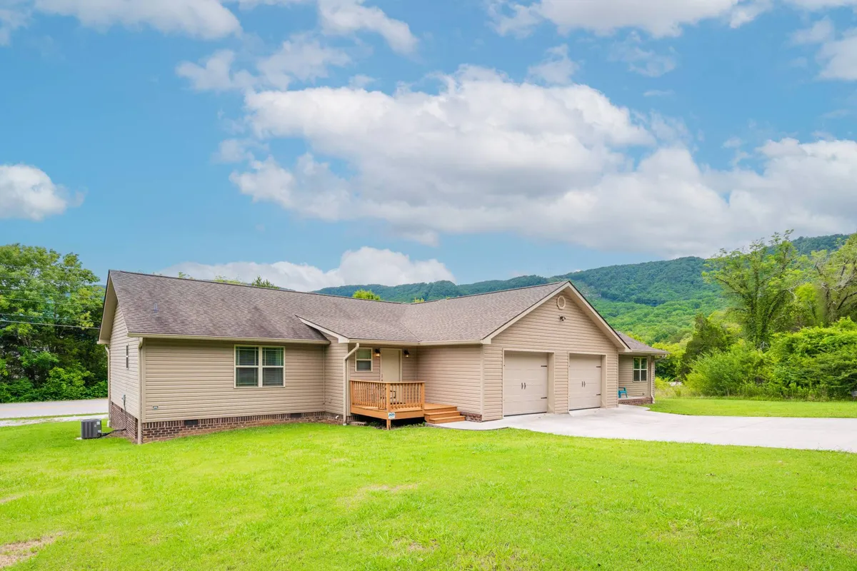 A charming single-family house with a welcoming front porch and a beautifully landscaped yard, set against a backdrop of Tennessee's scenic mountain views. The porch invites guests to relax and enjoy morning coffee or vibrant sunsets, while the spacious yard is perfect for gathering with family and friends.