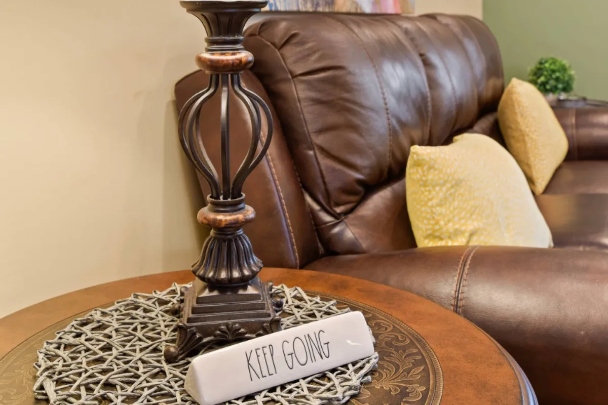 A living space featuring a sofa adorned with decorative pillows, a side lamp, and upbeat wall art. The arrangement encourages lighthearted conversation, reading, or unwinding with loved ones, capturing the spirit of relaxation and togetherness.